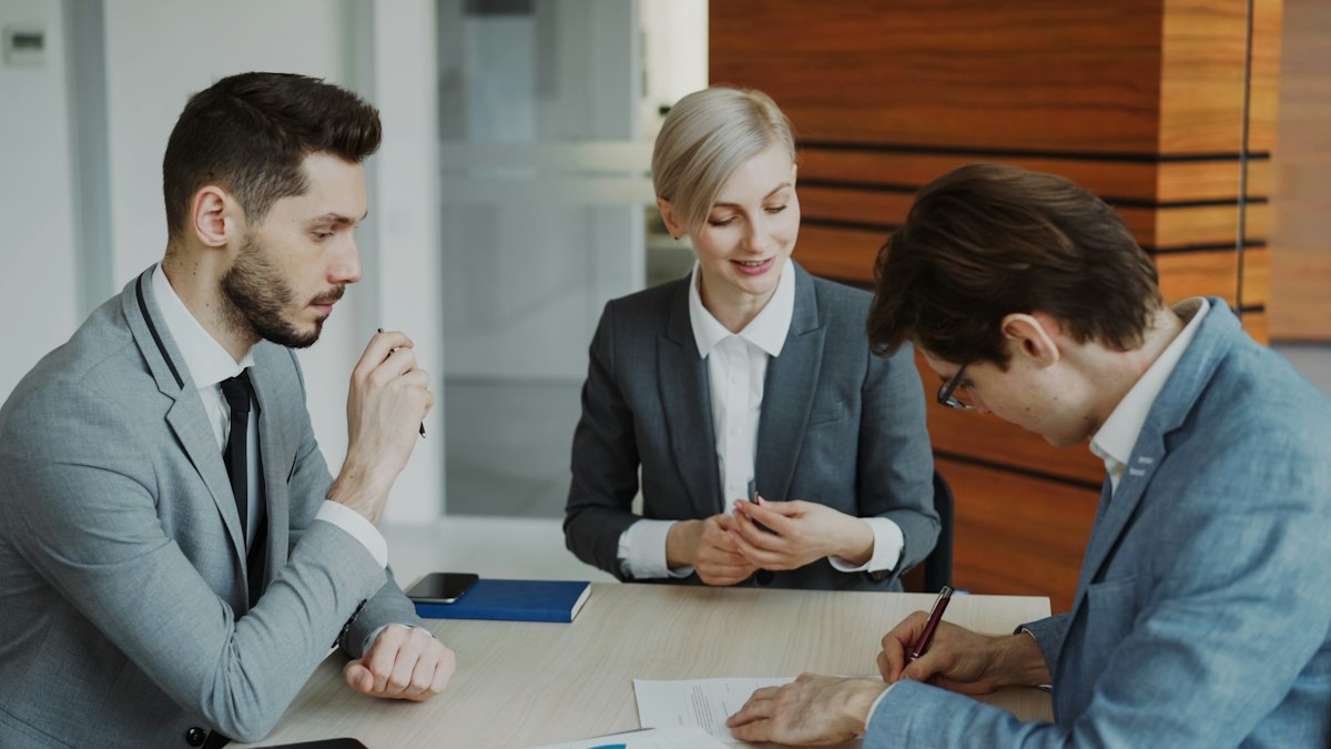Cliente assinando contrato acompanhado pelos advogados